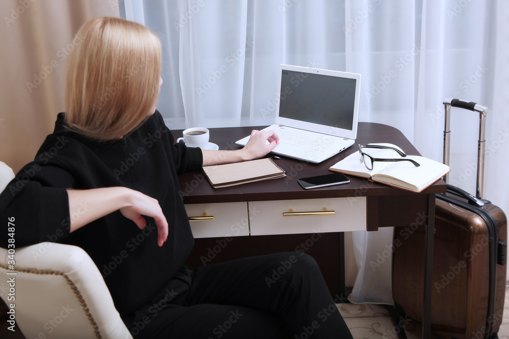 A young girl is working at a computer in a hotel room. Freelancer on a business trip. Copy of the space.Unrecognizable photo. A young girl is working at a computer in a hotel room. Freelancer on a business trip. Copy of the space.Unrecognizable photo.