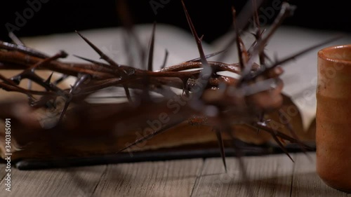 Cup being filled with wine with old Bible and Crown of Thorns panning right