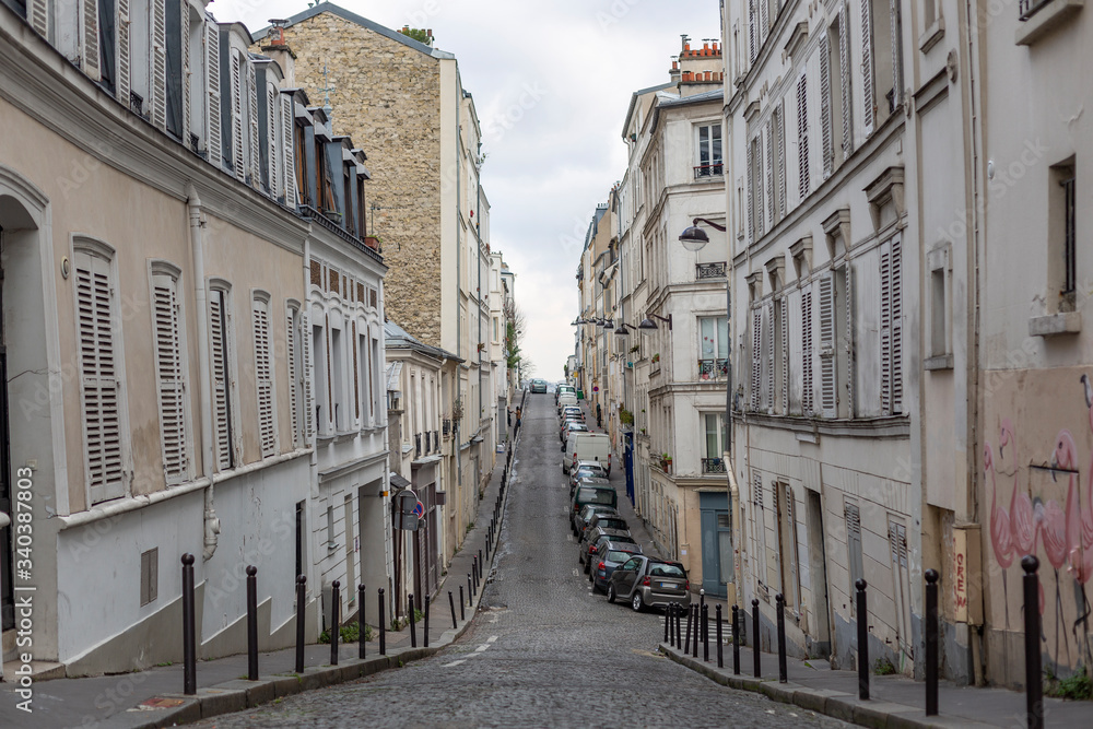 Fototapeta premium Horizontal view of a desertic street with a stoned road in Montmartre quarter of Paris, France