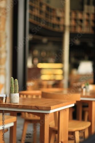 image of wooden table with cactus on top in front of abstract blurred background of restaurant lights