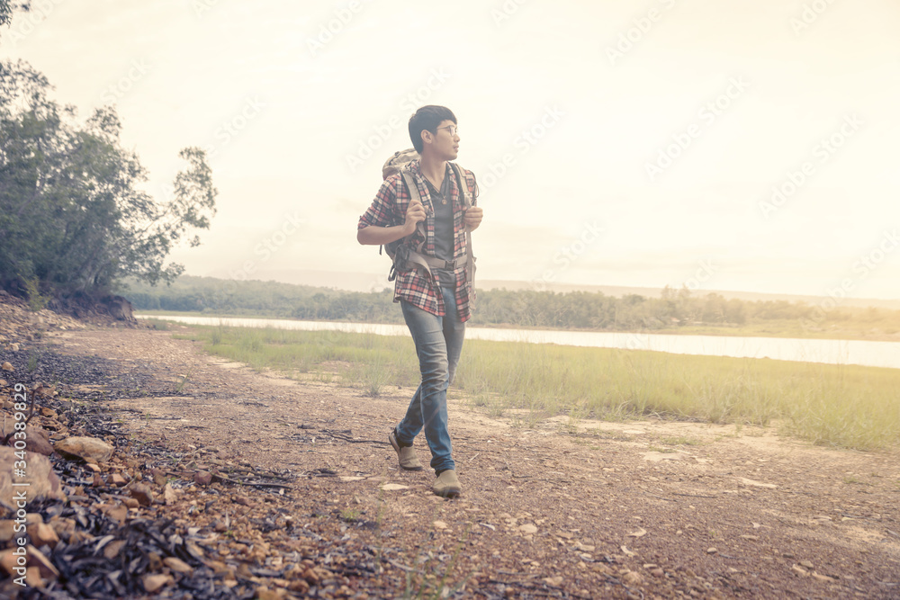 Man walking along have backpack for hiking. Camper camping / hiking / tour / travel. Have a romantic atmosphere / relaxation. The concept of camping and hiking. Man walking along have backpack for hiking. Camper camping / hiking / tour / travel. Have a romantic atmosphere / relaxation. The concept of camping and hiking.