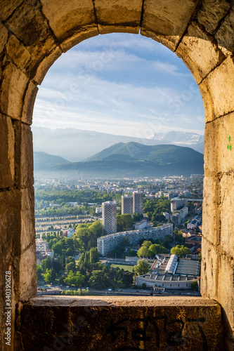 Looking out of an old stone window down on Grenoble France with snowy alps on the horizon