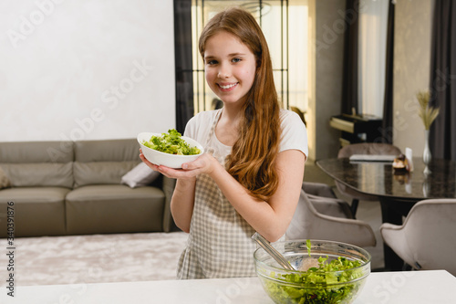 Happy girl with green salad in plate