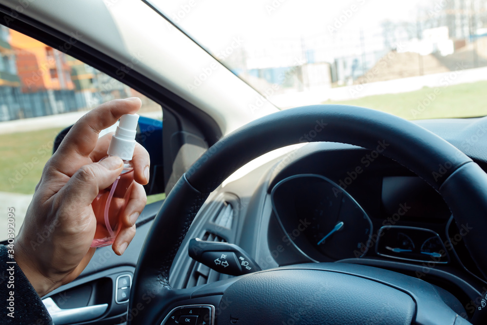 man hand spraying alcohol sanitizer on steering wheel in his car, Corona Virus Disease Covid 19. Antiseptic, Hygiene and Healthcare concept man hand spraying alcohol sanitizer on steering wheel in his car, Corona Virus Disease Covid 19. Antiseptic, Hygiene and Healthcare concept