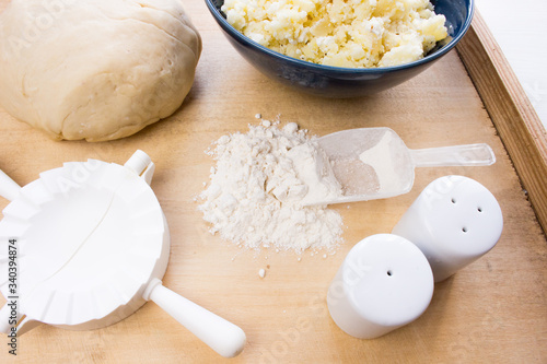 National Russian cuisine. Pierogi or pyrohy, vareniki, served with cottage cheese and potatoes on board.  Raw dumplings made of dough in handmade flour photo