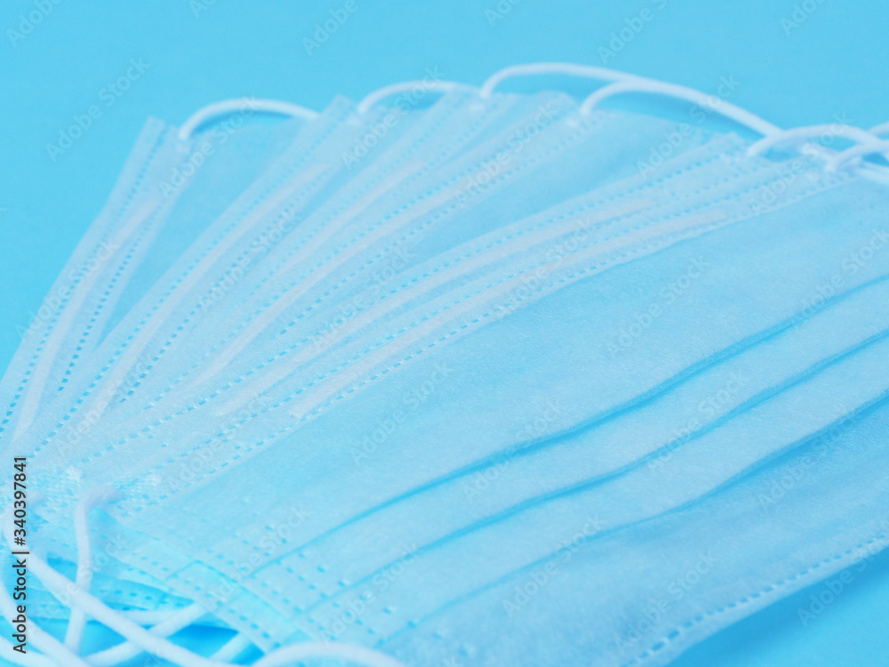 Obraz premium Surgical protective face masks are laid out on a blue background. Concept of protection against viruses and bacteria.