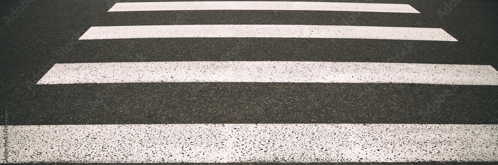 Fototapeta premium modern pedestrian crossing with white stripes on city road at sunlight closeup