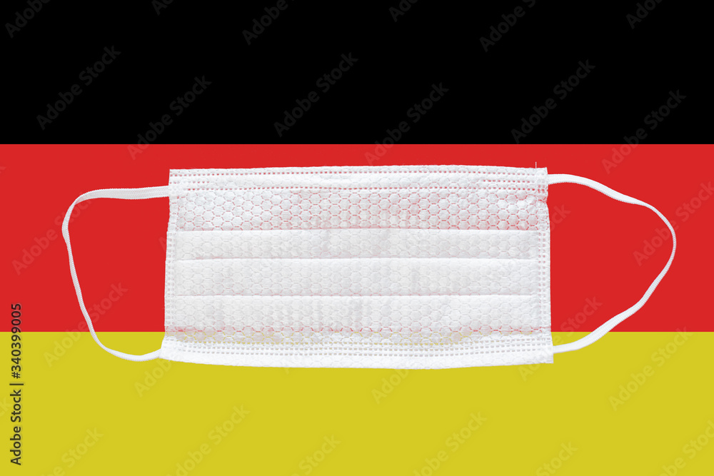 Obraz premium Coronavirus in Germany. Medical mask on the background of the flag
