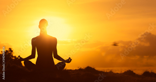 Fototapeta Naklejka Na Ścianę i Meble -  Meditation silhouette of you female sitting facing the beautiful sunrise. 
