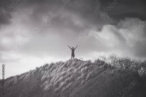 Victory on top a mountain. Man feeling strong, and inspired with arms up to the sky. 