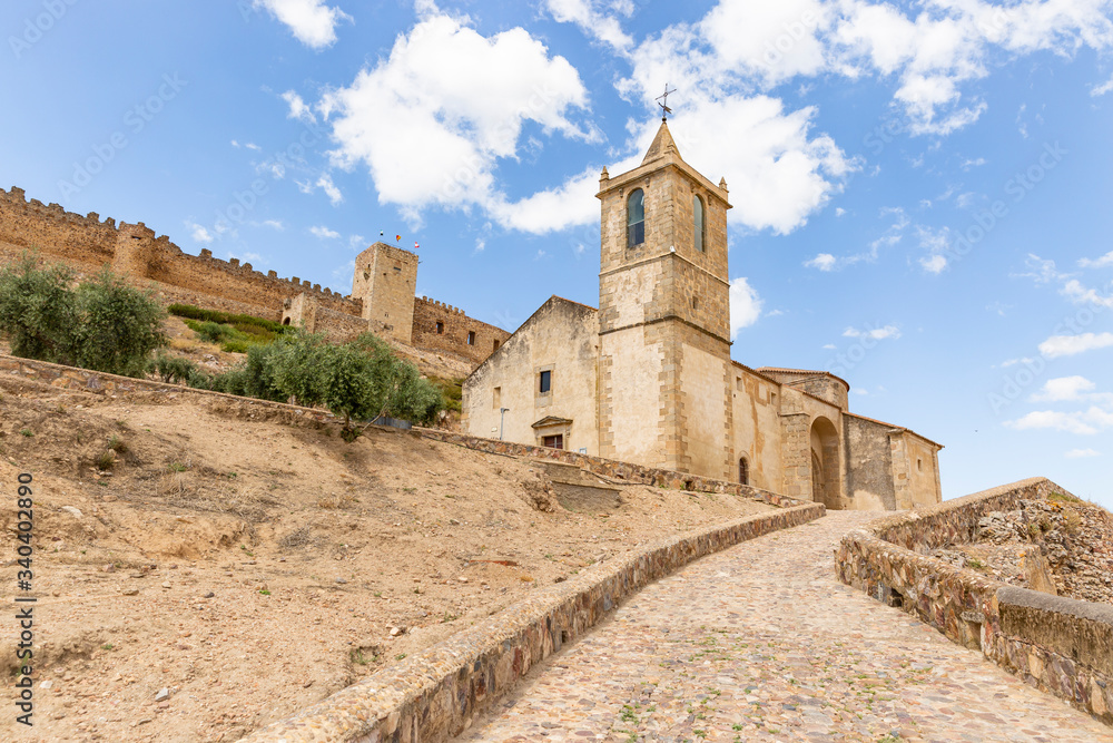 Santiago church with the medieval castle in the background in Medellin, comarca de Vegas Altas, province of Badajoz, Extremadura, Spain