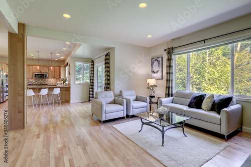 Large  bright and open space with grey sofas and white rug and kitchen with modern stools.