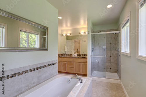 Large classic master bedroom bathroom with walkin in shower, buil in tub and wood cabinets with two sinks.