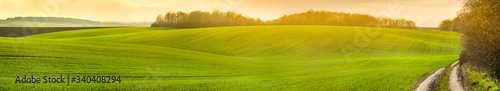 panoramic view of farmland in hilly countryside at sunset in spring