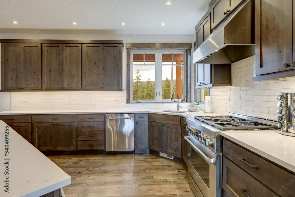 Luxury dark wood rich kitchen interior with white subway tiles backsplash and quarts countertop.