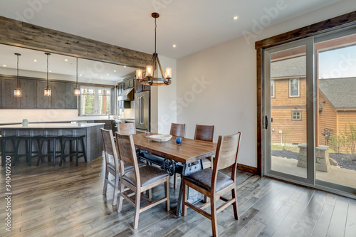 Open bright living room with long rustic wooden table and metal modern and kitchen.