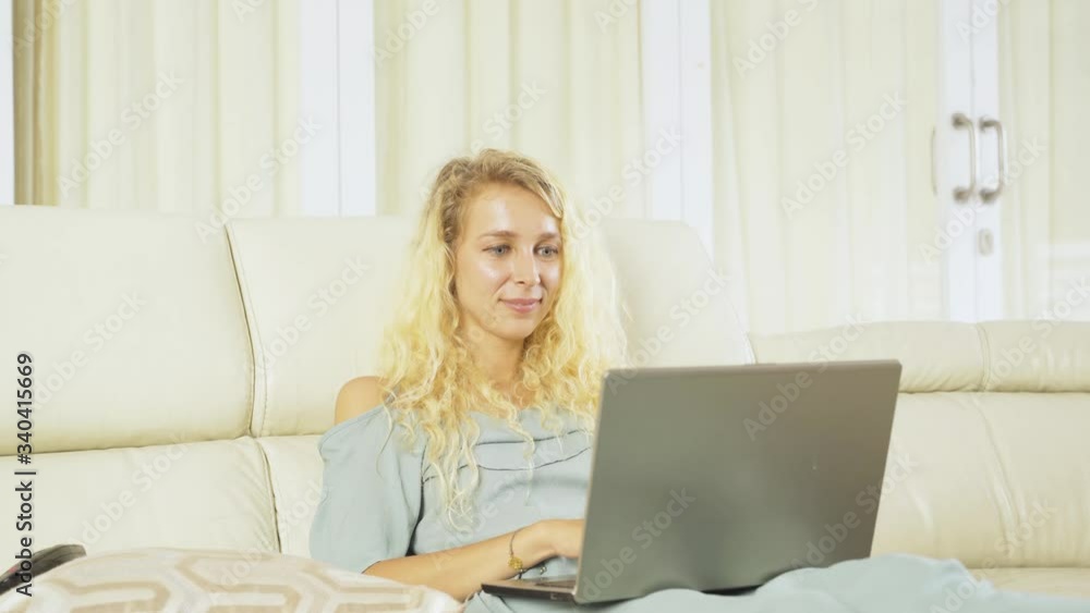 Young blonde woman using a computer laptop while expressing her success or achievement on the couch at home. Shot in 4k resolution Young blonde woman using a computer laptop while expressing her success or achievement on the couch at home. Shot in 4k resolution