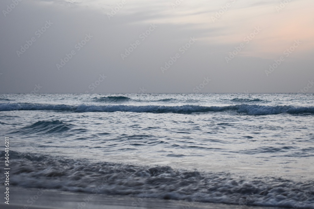 Waves are hitting the beach in the evening before sunset