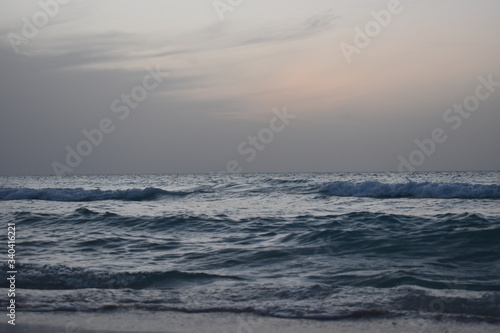 Waves are hitting the beach in the evening before sunset