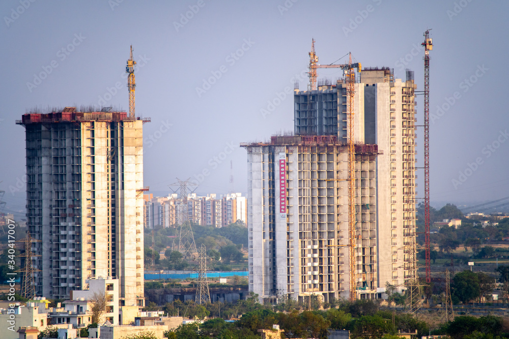 Aerial shot of under construction building with multiple floors and crane at the top standing out in the countryside. Shows the rapid development of skyscrapers even in the most rural areas with the