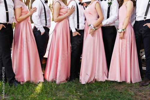 Classic wedding. Bridesmaids in pink dresses and groomsmen in black trousers and white shirts with suspender at wedding day