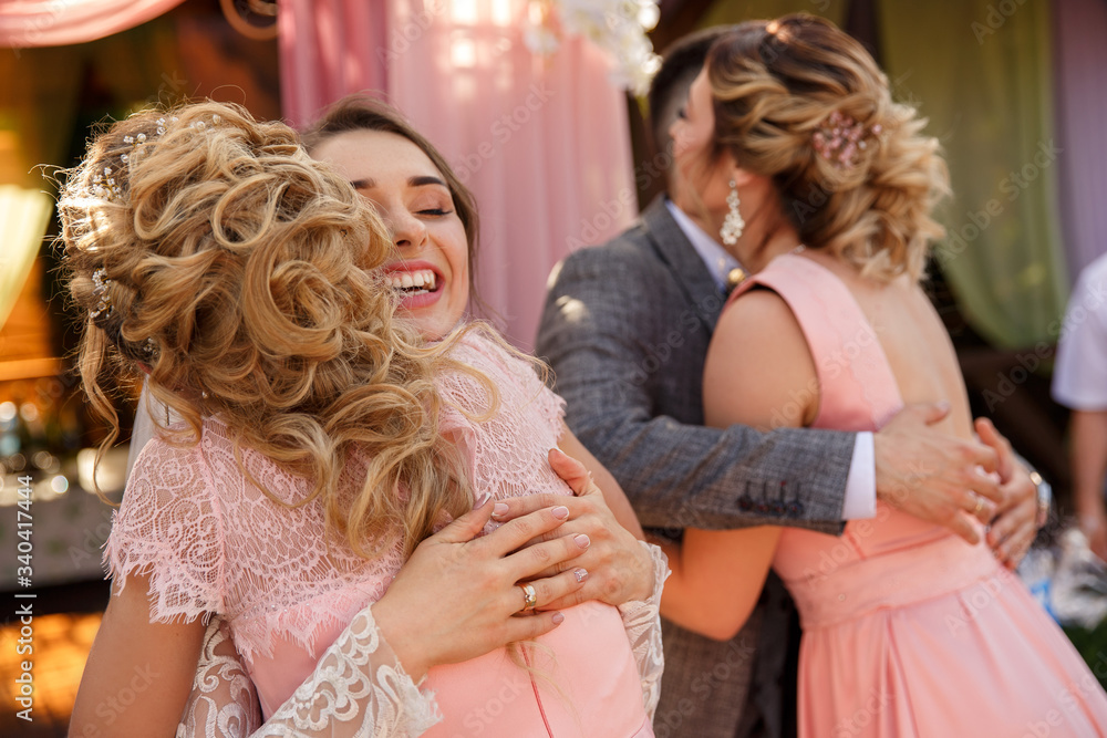 Happy momemt of wedding day. Bridesmaids congratulate the bride and groom after wedding ceremony