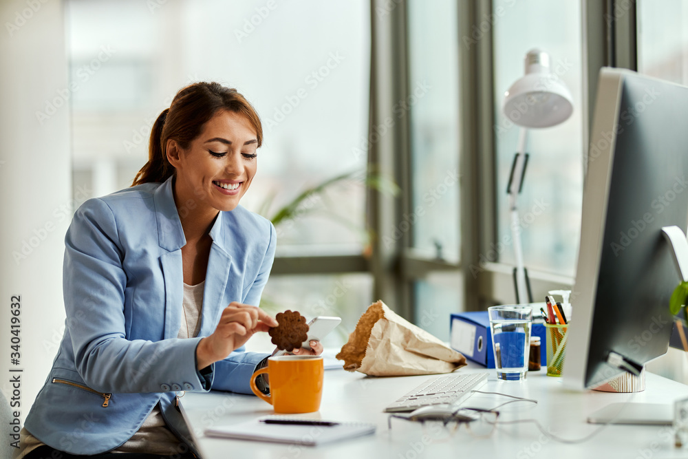 Young businesswoman eating cookie on a break in the office. Young businesswoman eating cookie on a break in the office.