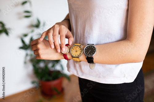 close up photo of female hands wearing three different hand watches with different numerals. Black, yellow and read wrist watch. 