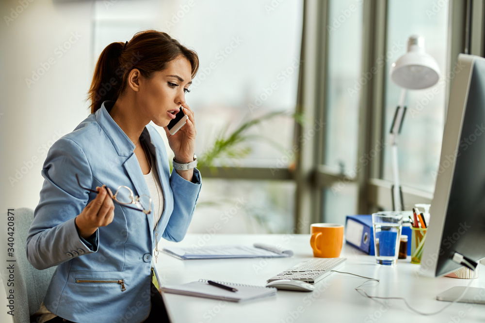 Young businesswoman talking on cell phone while working in the office. Young businesswoman talking on cell phone while working in the office.