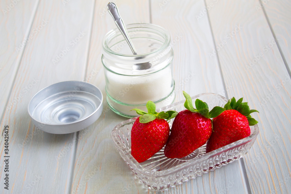 delicious red strawberries next to bowl with sugar and a spoon delicious red strawberries next to bowl with sugar and a spoon