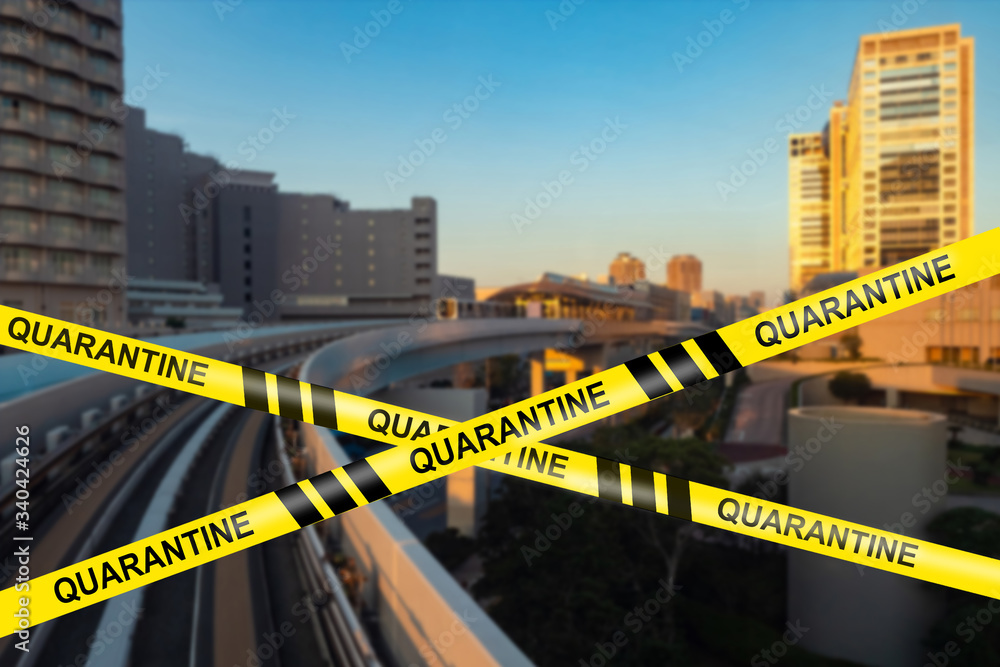 Yellow restraining tape with the word Quarantine on the background of the city. Coronavirus quarantine. The city has declared a Covid-19 quarantine. Isolation mode.