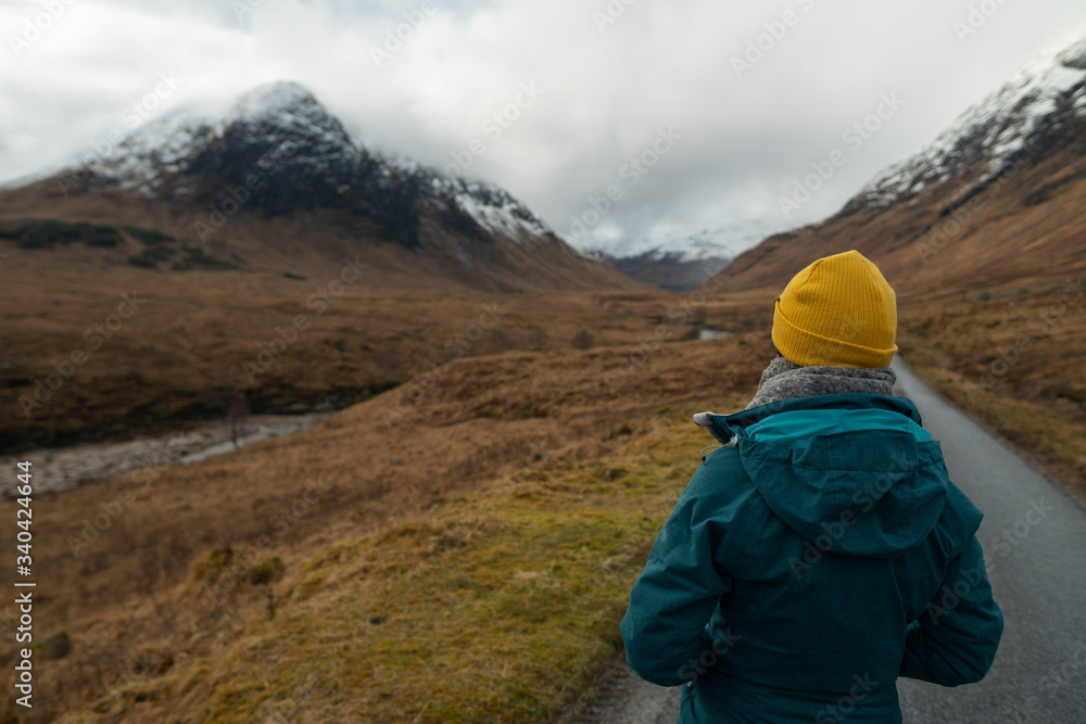 Beautiful shot of girl standing on scenic road in Glen Etive, Glen Coe Scotland. Landscape in rainy foggy weather. Place where famous was filmed. Beautiful shot of girl standing on scenic road in Glen Etive, Glen Coe Scotland. Landscape in rainy foggy weather. Place where famous was filmed.