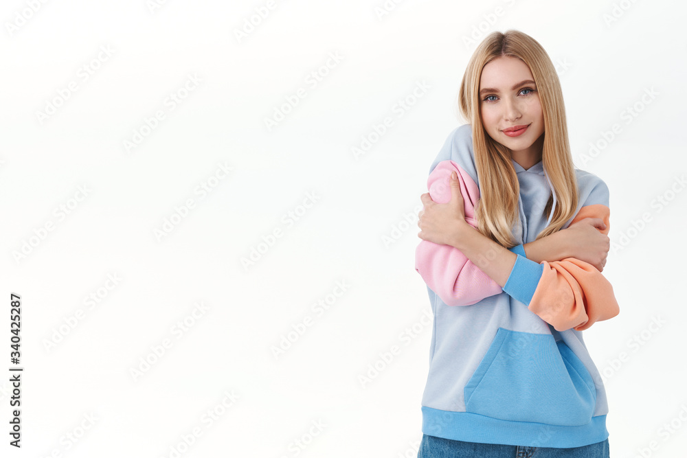 Portrait of romantic, tender young beautiful blonde girl, want person comfort her, cuddling herself, embracing own hands over body and smiling, need feel warmth and love, white background Portrait of romantic, tender young beautiful blonde girl, want person comfort her, cuddling herself, embracing own hands over body and smiling, need feel warmth and love, white background