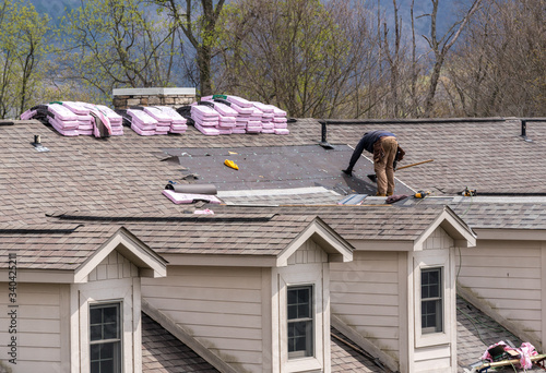 Roofing contractor removing the old tiles before replacing with new shingles on a townhouse roof photo