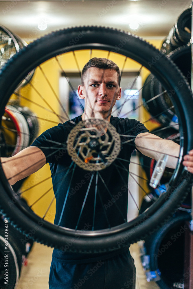 Guy is repairing a bicycle in a bicycle workshop Guy is repairing a bicycle in a bicycle workshop