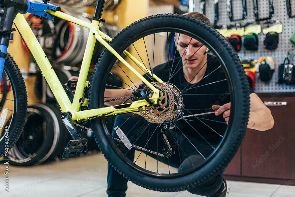 Guy is repairing a bicycle in a bicycle workshop Guy is repairing a bicycle in a bicycle workshop