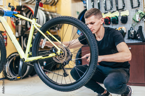 Guy is repairing a bicycle in a bicycle workshop