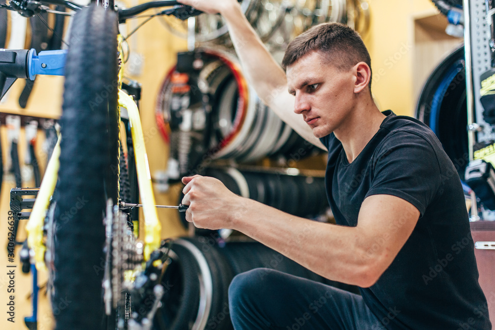 Obraz premium Guy is repairing a bicycle in a bicycle workshop
