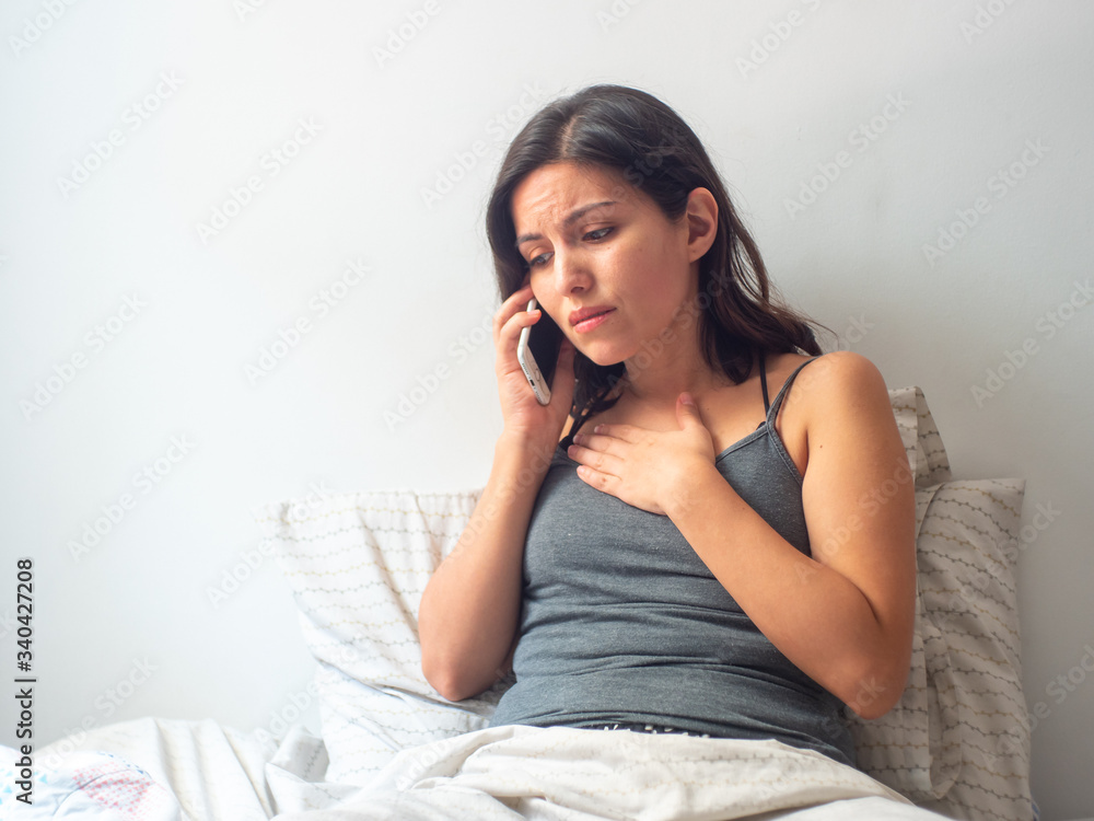 Young Brown Hair Hispanic Female Staying at Home and Speaking Worried at the Phone in her Bed in Quarantine Young Brown Hair Hispanic Female Staying at Home and Speaking Worried at the Phone in her Bed in Quarantine