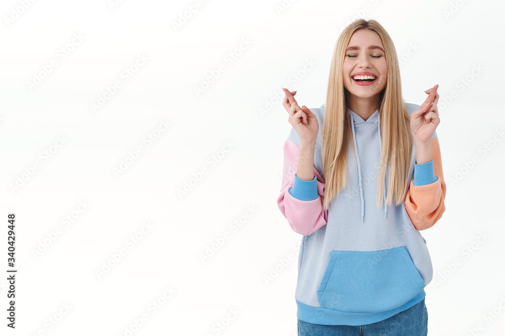 Hopeful, enthusiastic and optimistic smiling blonde girl close eyes, making wish with fingers crossed, dreaming for relish and positive results, want dream come true, wishing over white background Hopeful, enthusiastic and optimistic smiling blonde girl close eyes, making wish with fingers crossed, dreaming for relish and positive results, want dream come true, wishing over white background