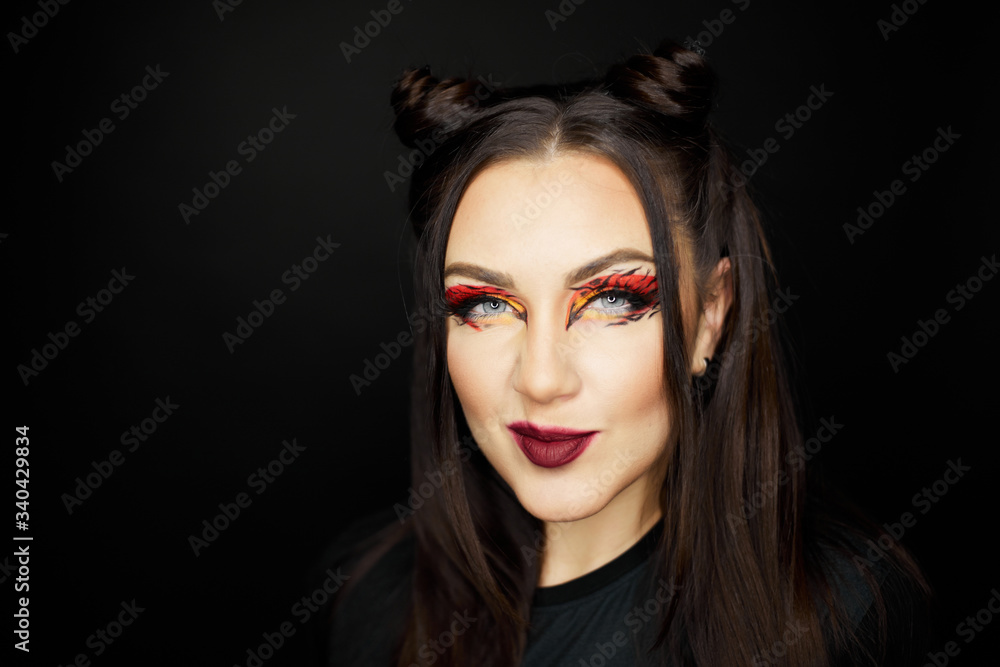 Fototapeta premium Fashion beauty portrait of a beautiful young girl. Makeup cat. Sexy woman with koshachmi ears on the hair. Face of the beautiful woman with long brown hair posing at studio over dark background.