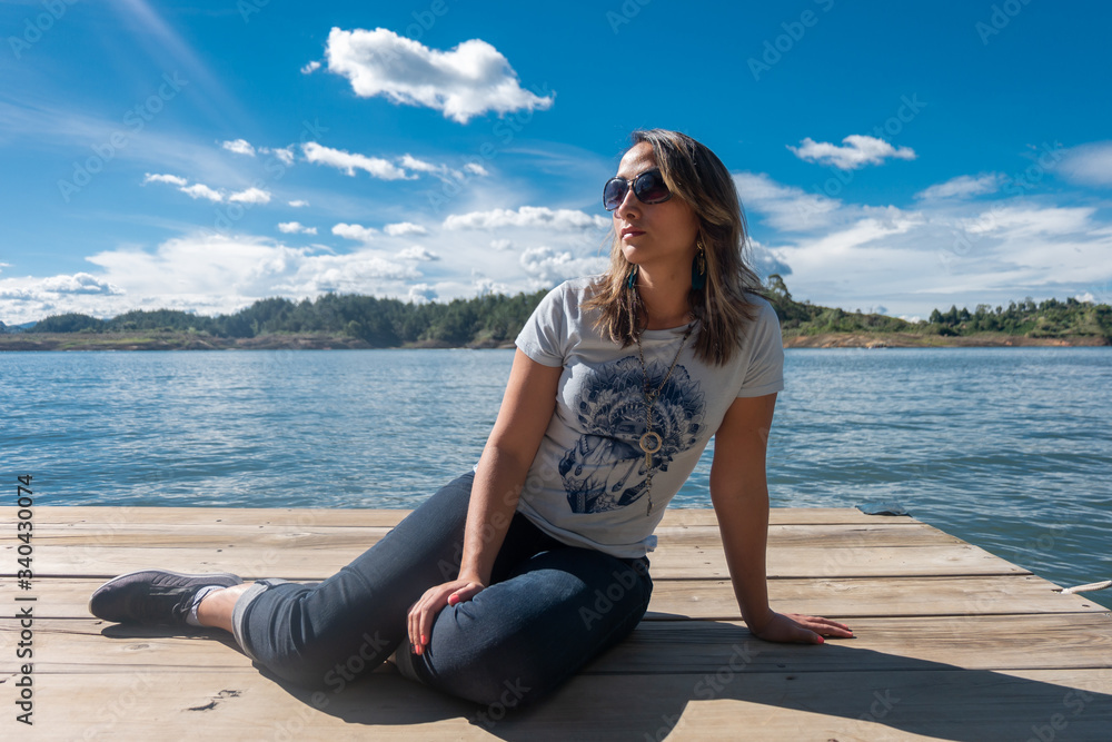 Young woman with sunglasses on a small wooden platform in Lake Guatapé, Antioquia, Colombia