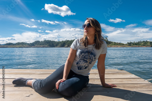 Obraz na płótnie Young woman with sunglasses on a small wooden platform in Lake Guatapé, Antioquia, Colombia w salonie
