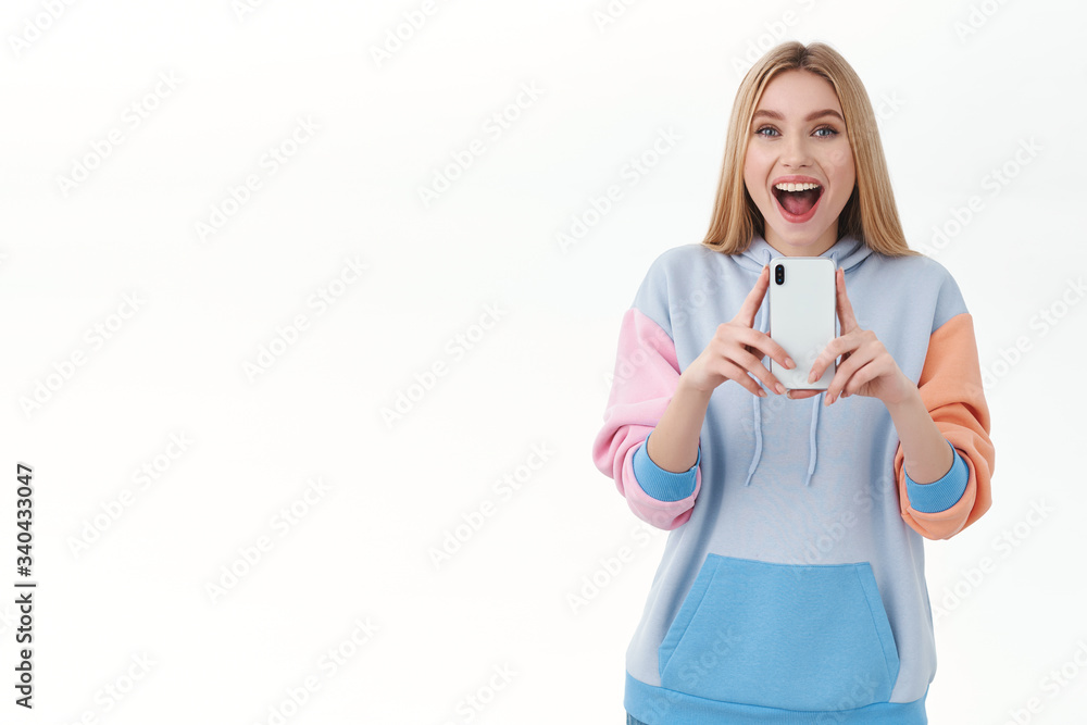 Communication, technology and online concept. Excited happy female blonde in hoodie, record video on mobile phone, taking photo and smiling, blogger creating new content for social media
