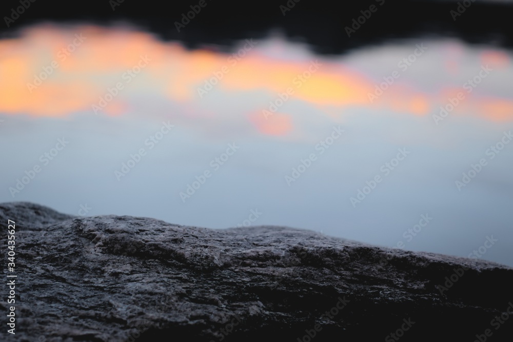 Calm, serene natural environment. Rock texture close up against twilight sky reflections on a lake. Calm, serene natural environment. Rock texture close up against twilight sky reflections on a lake.