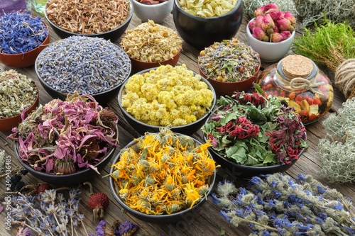 Bowls of dry medicinal herbs - lavender, cornflower, echinacea, marigold, rose, daisies, oak bark, Helichrysum, healthy moss and lichen. Healing herbs assortment. Herbal medicine. photo