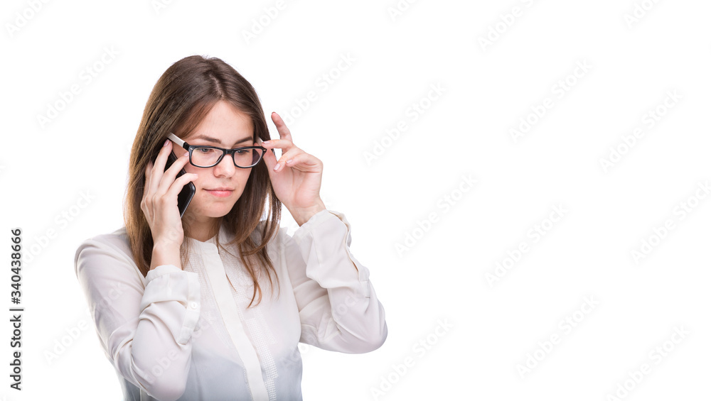 Smiling businesswoman in glasses talking on mobile phone. Beautiful young girl in white shirt on white isolated background talking on mobile phone. Woman in shirt with cellphone. Copy space. Blank Smiling businesswoman in glasses talking on mobile phone. Beautiful young girl in white shirt on white isolated background talking on mobile phone. Woman in shirt with cellphone. Copy space. Blank