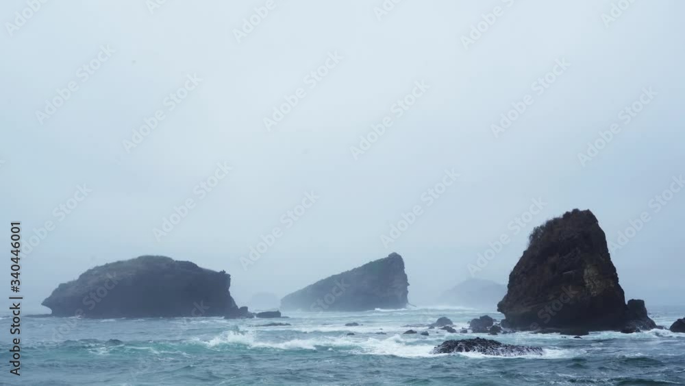 Beautiful scenery of misty morning at Papuma beach with big corals in Jember at East Java, Indonesia. Shot in 4k resolution