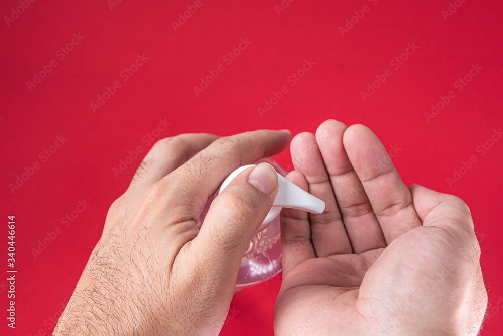 Man hand in container with alcohol gel on the red background Man hand in container with alcohol gel on the red background