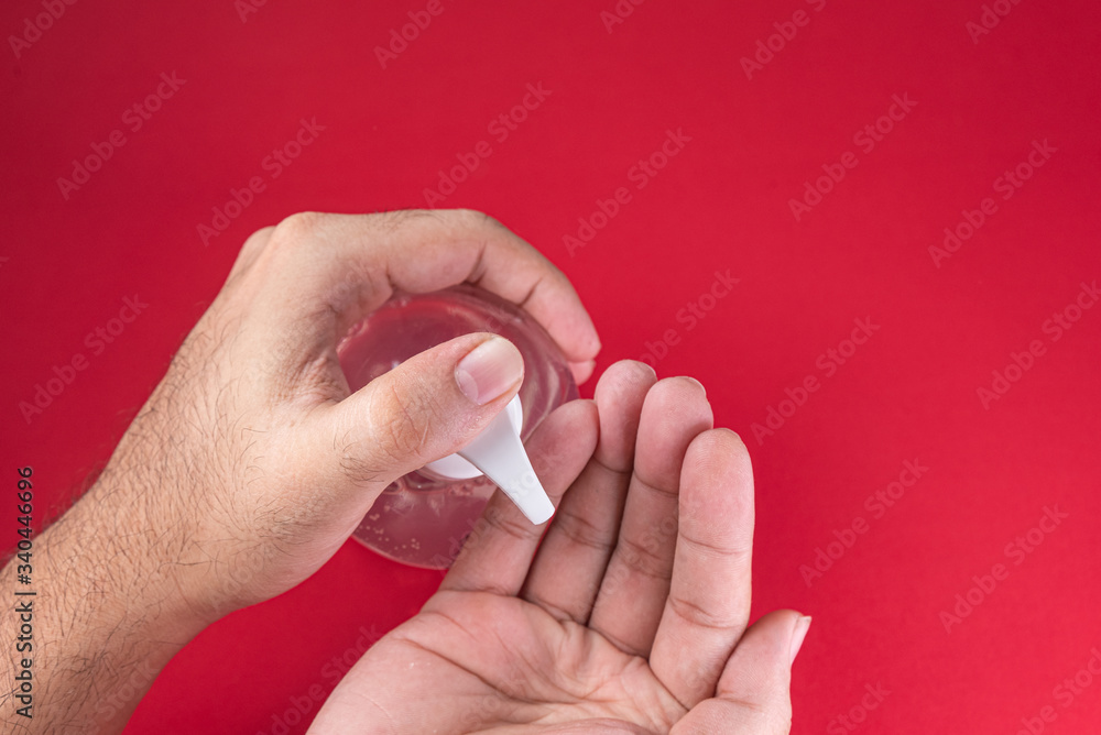 Man hand in container with alcohol gel on the red background Man hand in container with alcohol gel on the red background